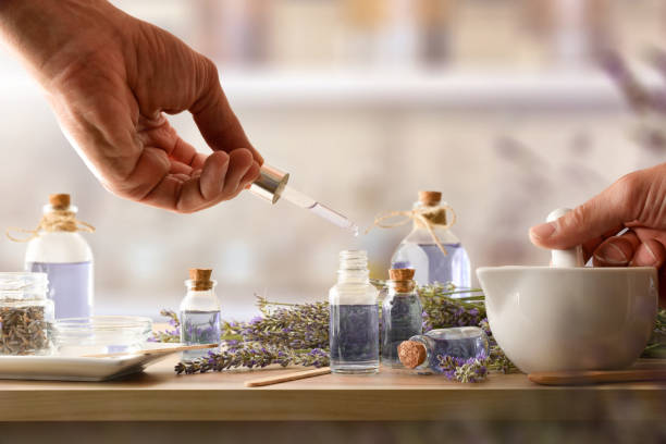 Hands-making lavender oil with natural ingredients and dropper bottles.