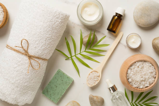 Spa essentials with a towel, sea salt, essential oils, and natural soap
