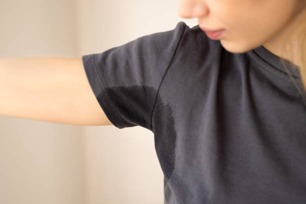 a woman wearing a dark t-shirt with a visible underarm sweat stain