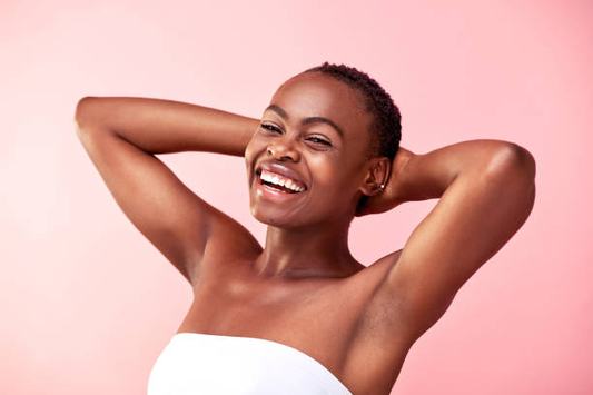 Smiling woman with short hair and smooth skin, posing confidently with hands behind her head